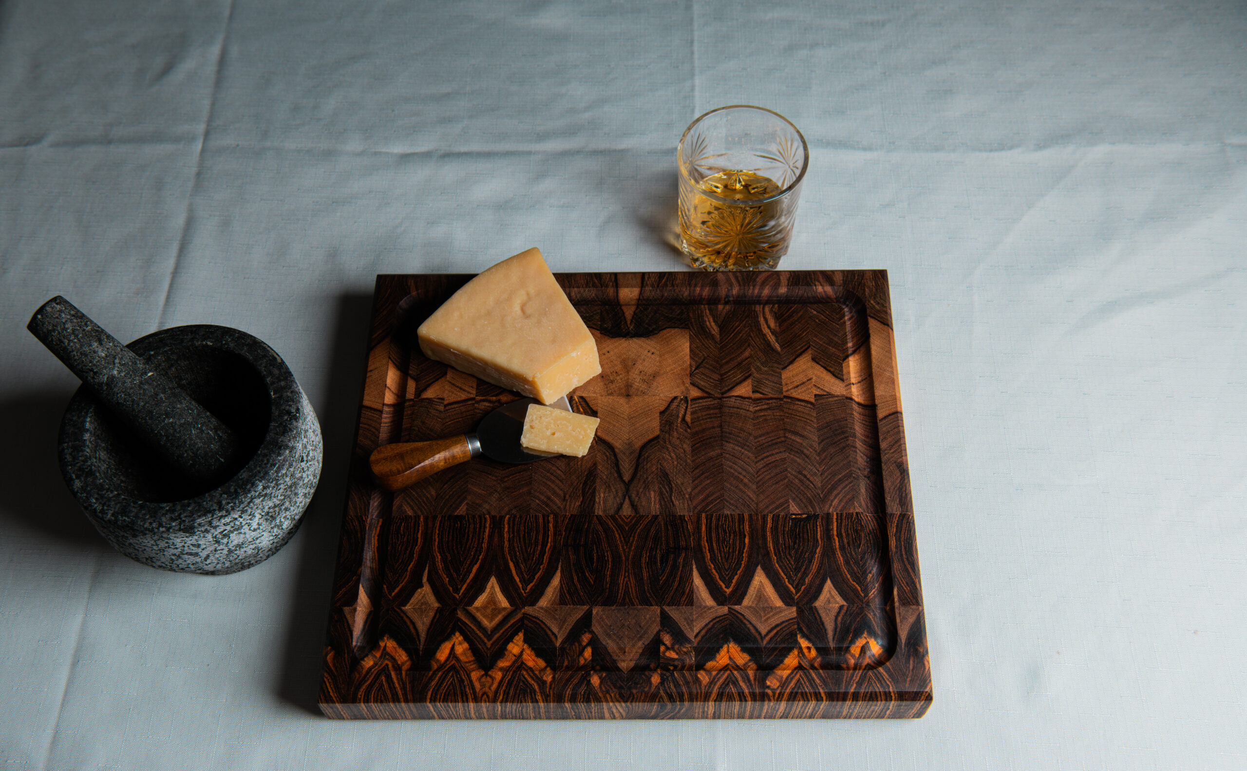 cutting board with cheese and a drink